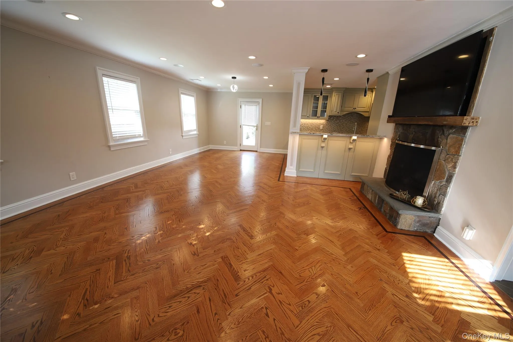 Unfurnished living room featuring ornamental molding, recessed lighting, and a stone fireplace Unfurnished living room featuring ornamental molding, recessed lighting, and a stone fireplace