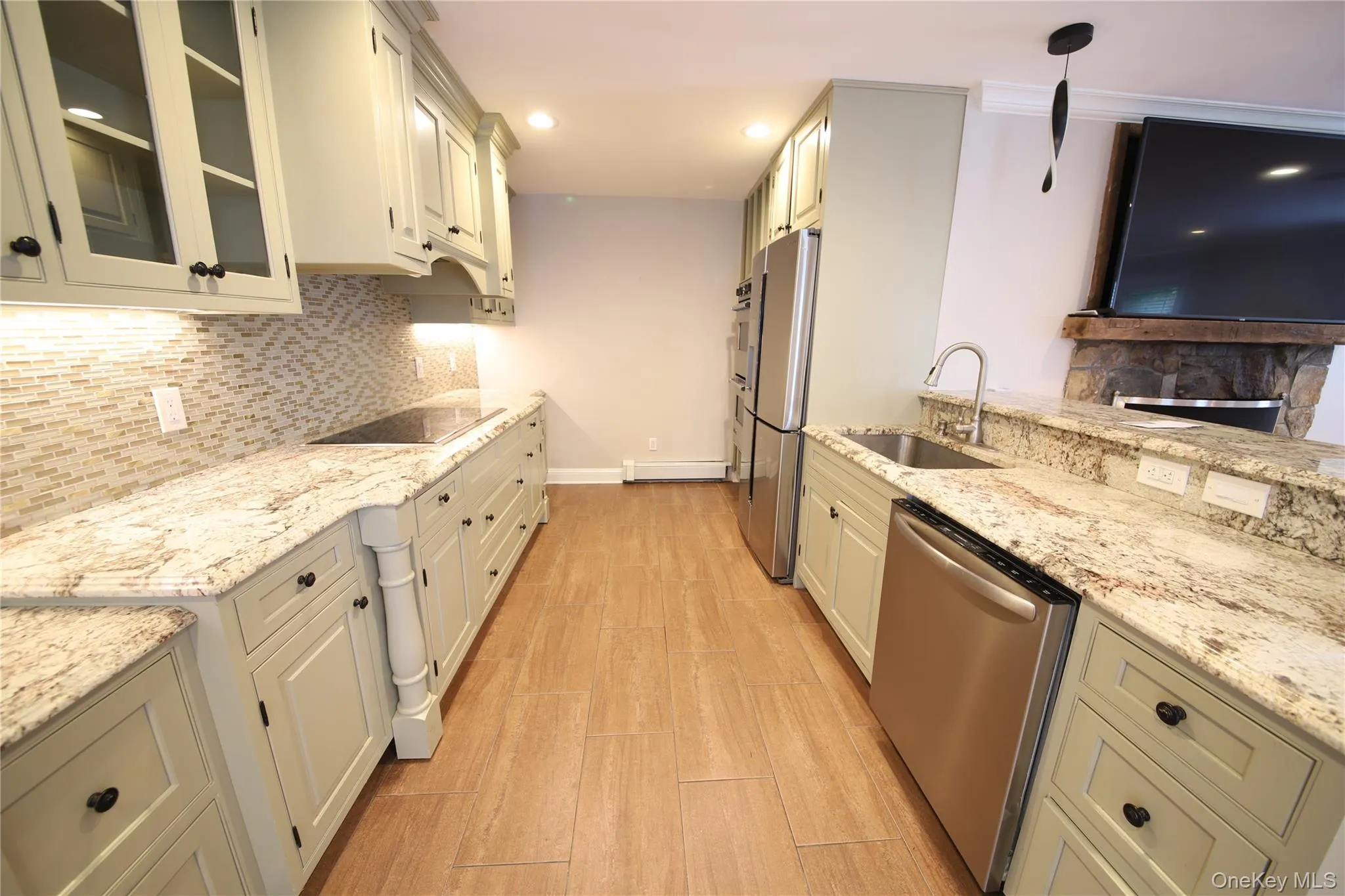 Kitchen with light stone countertops, tasteful backsplash, glass insert cabinets, appliances with stainless steel finishes, and hanging light fixtures Kitchen with light stone countertops, tasteful backsplash, glass insert cabinets, appliances with stainless steel finishes, and hanging light fixtures