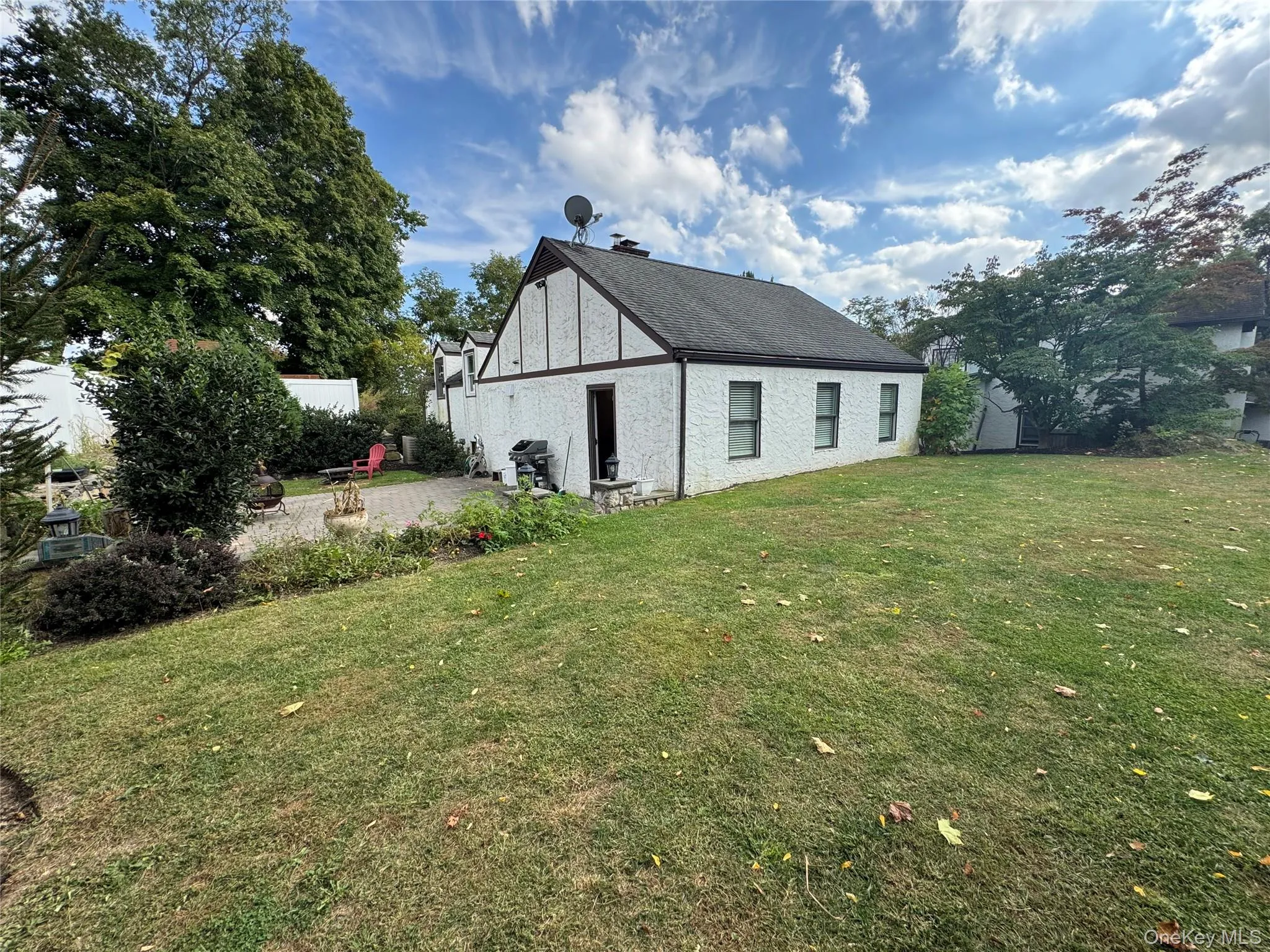 Back of property with a lawn, a shingled roof, and a patio area Back of property with a lawn, a shingled roof, and a patio area