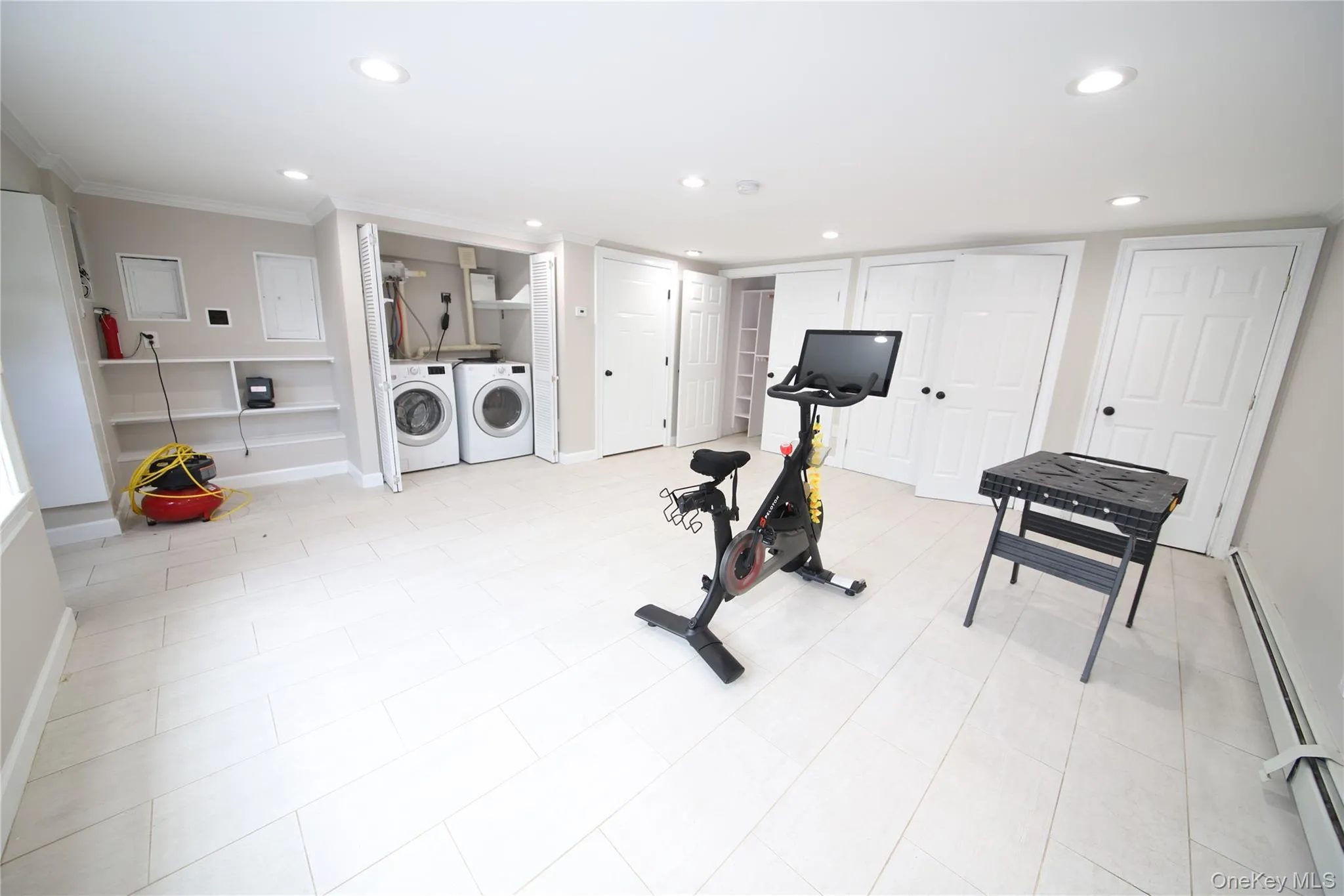 Exercise room with a baseboard radiator, recessed lighting, washing machine and clothes dryer, and crown molding Exercise room with a baseboard radiator, recessed lighting, washing machine and clothes dryer, and crown molding