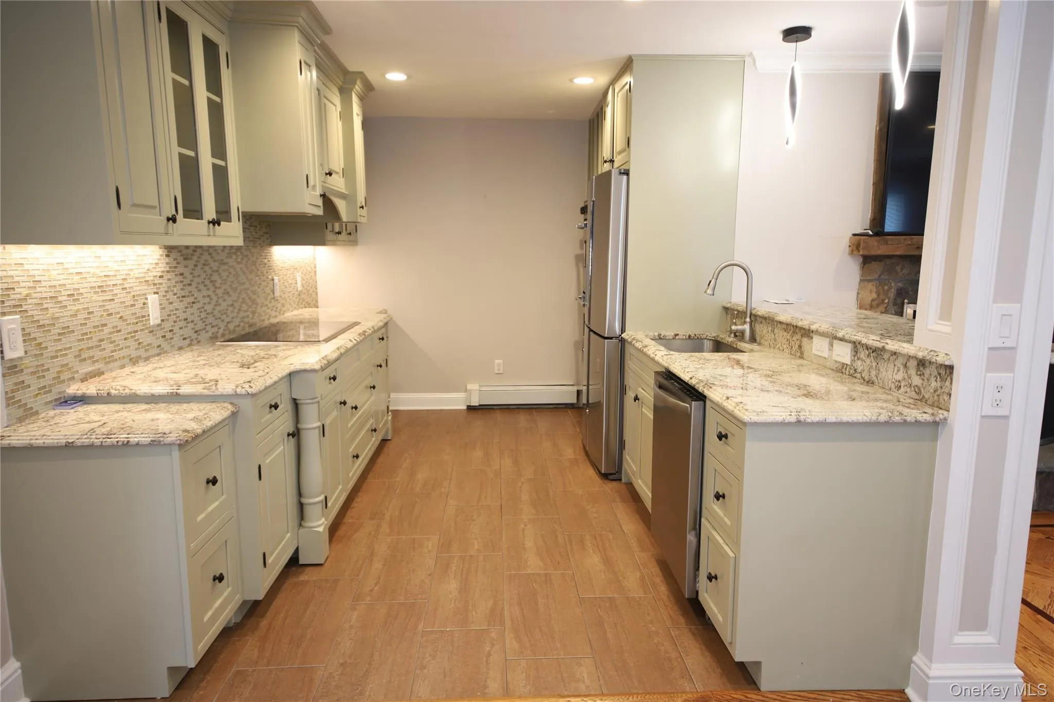 Kitchen featuring light stone counters, tasteful backsplash, glass insert cabinets, appliances with stainless steel finishes, and pendant lighting Kitchen featuring light stone counters, tasteful backsplash, glass insert cabinets, appliances with stainless steel finishes, and pendant lighting