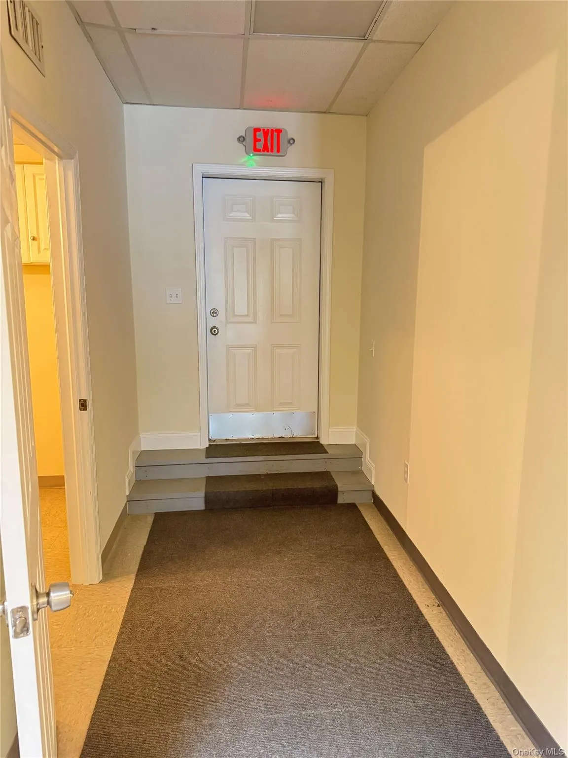 Corridor with a paneled ceiling and baseboards Corridor with a paneled ceiling and baseboards