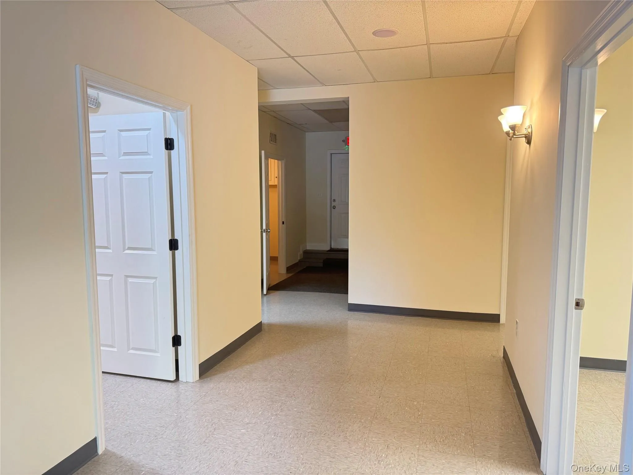 Corridor featuring a drop ceiling and light floors Corridor featuring a drop ceiling and light floors