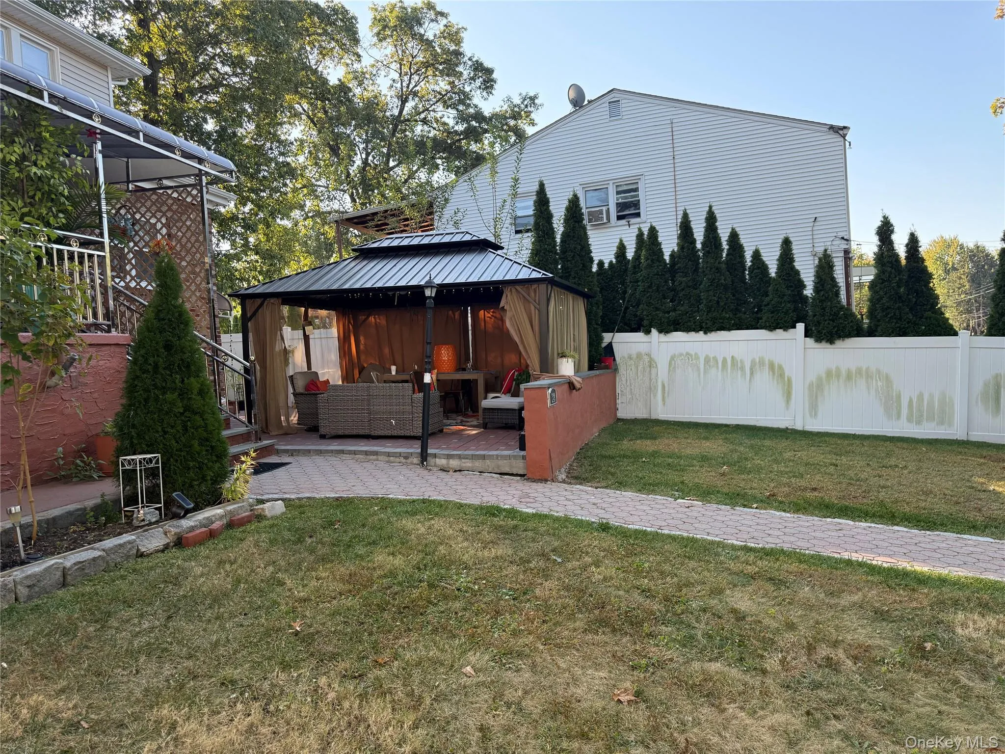 Fenced backyard with outdoor lounge area, a wooden deck, and a gazebo Fenced backyard with outdoor lounge area, a wooden deck, and a gazebo