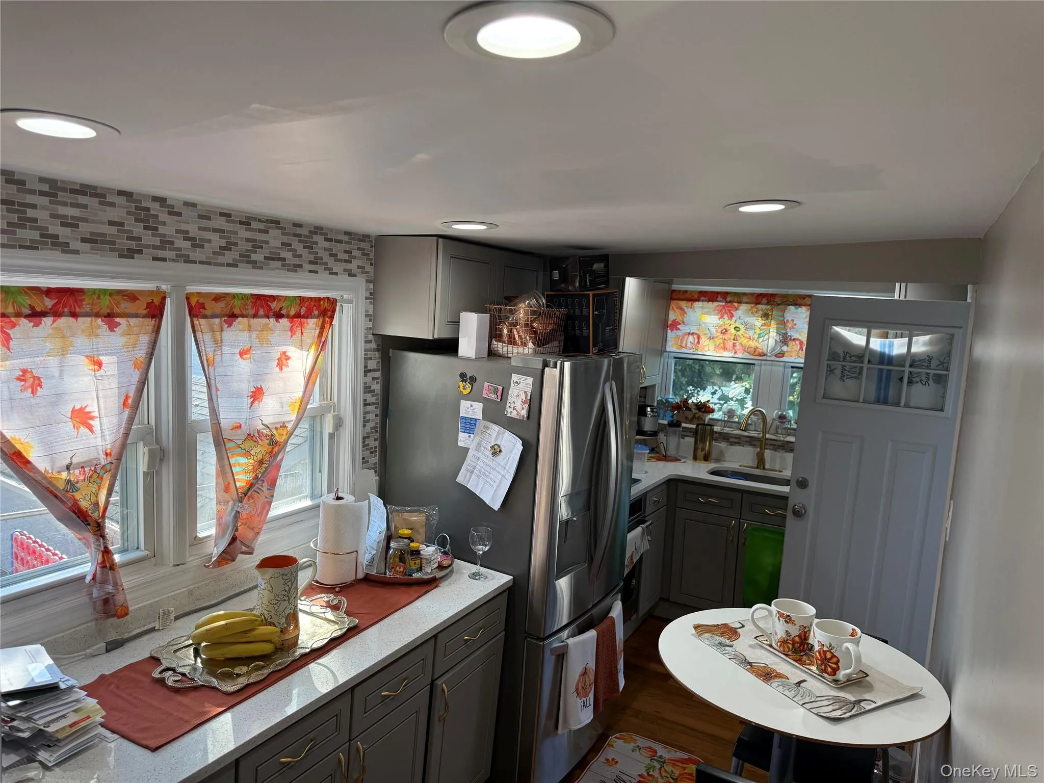 Kitchen with gray cabinets, appliances with stainless steel finishes, light stone countertops, dark wood-type flooring, and recessed lighting Kitchen with gray cabinets, appliances with stainless steel finishes, light stone countertops, dark wood-type flooring, and recessed lighting