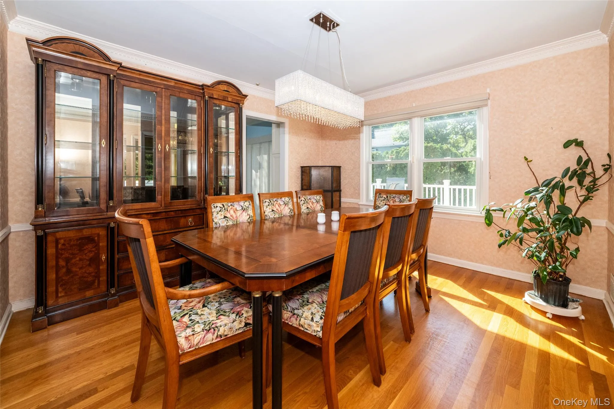 Dining area with wallpapered walls, ornamental molding, and light wood-style floors Dining area with wallpapered walls, ornamental molding, and light wood-style floors