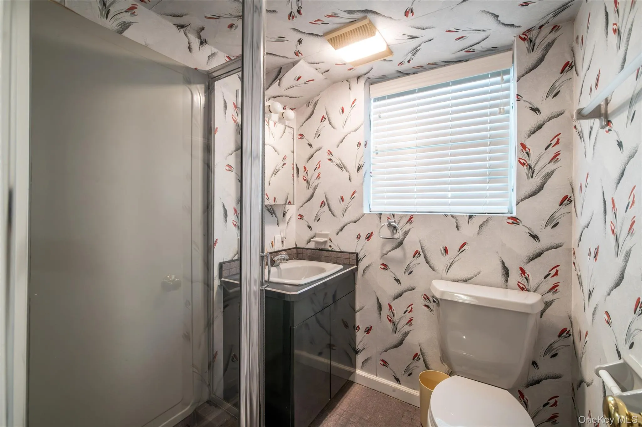 Full bathroom with vanity, wallpapered walls, and a stall shower Full bathroom with vanity, wallpapered walls, and a stall shower