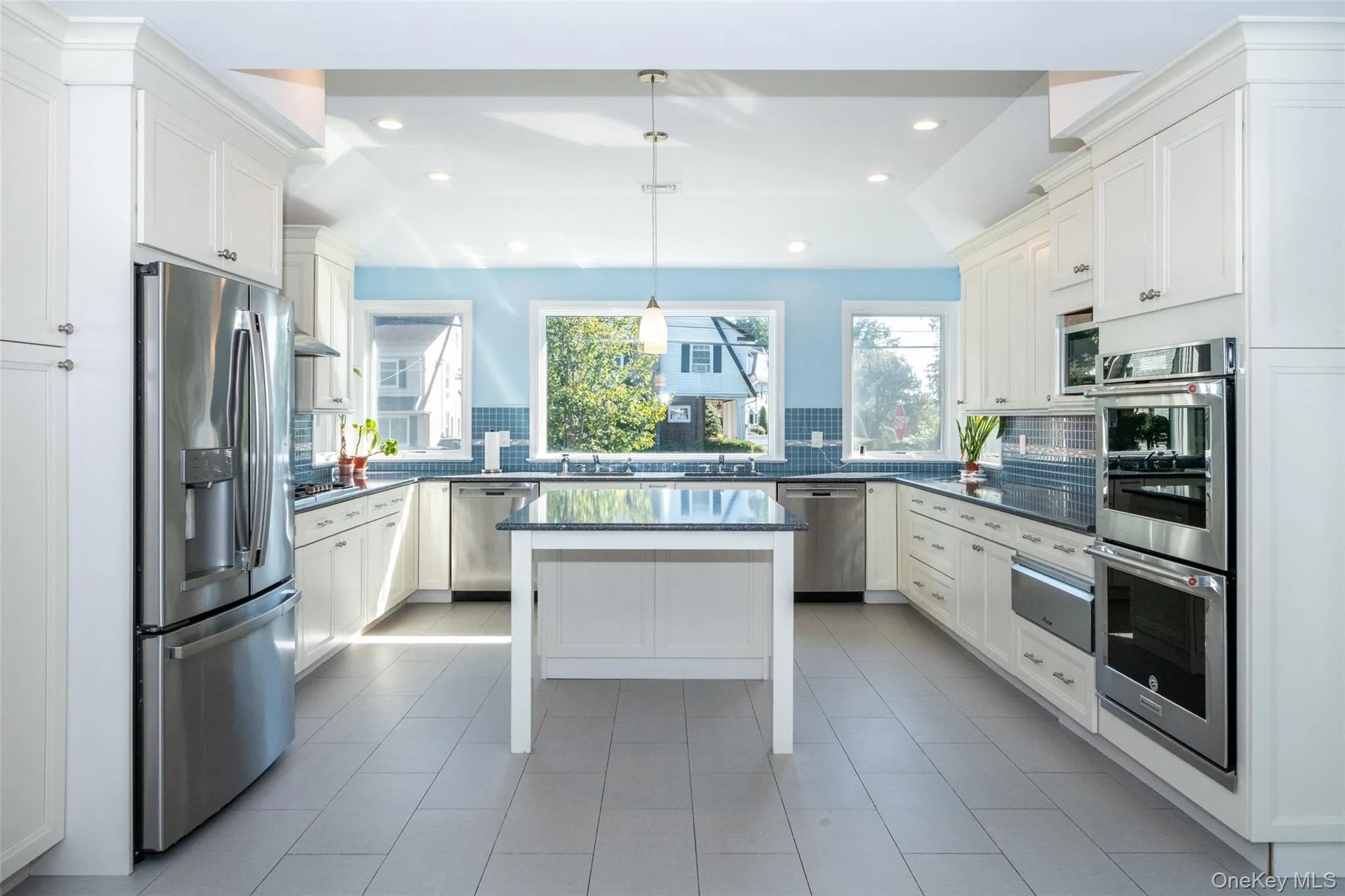 Kitchen with appliances with stainless steel finishes, pendant lighting, white cabinets, decorative backsplash, and recessed lighting Kitchen with appliances with stainless steel finishes, pendant lighting, white cabinets, decorative backsplash, and recessed lighting