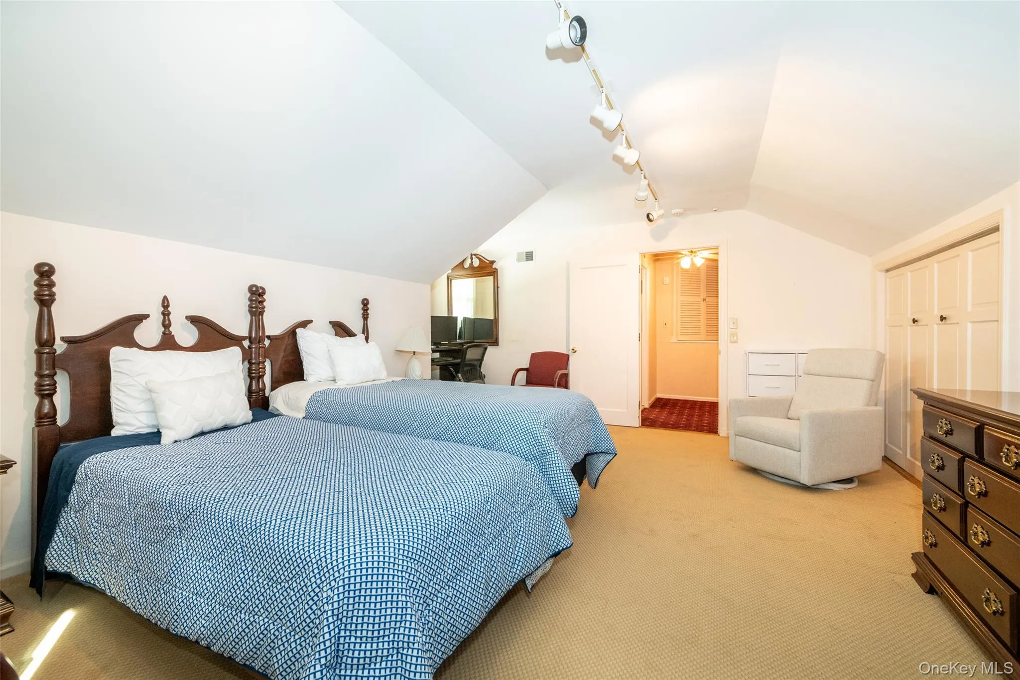 Bedroom with vaulted ceiling, light colored carpet, and rail lighting Bedroom with vaulted ceiling, light colored carpet, and rail lighting