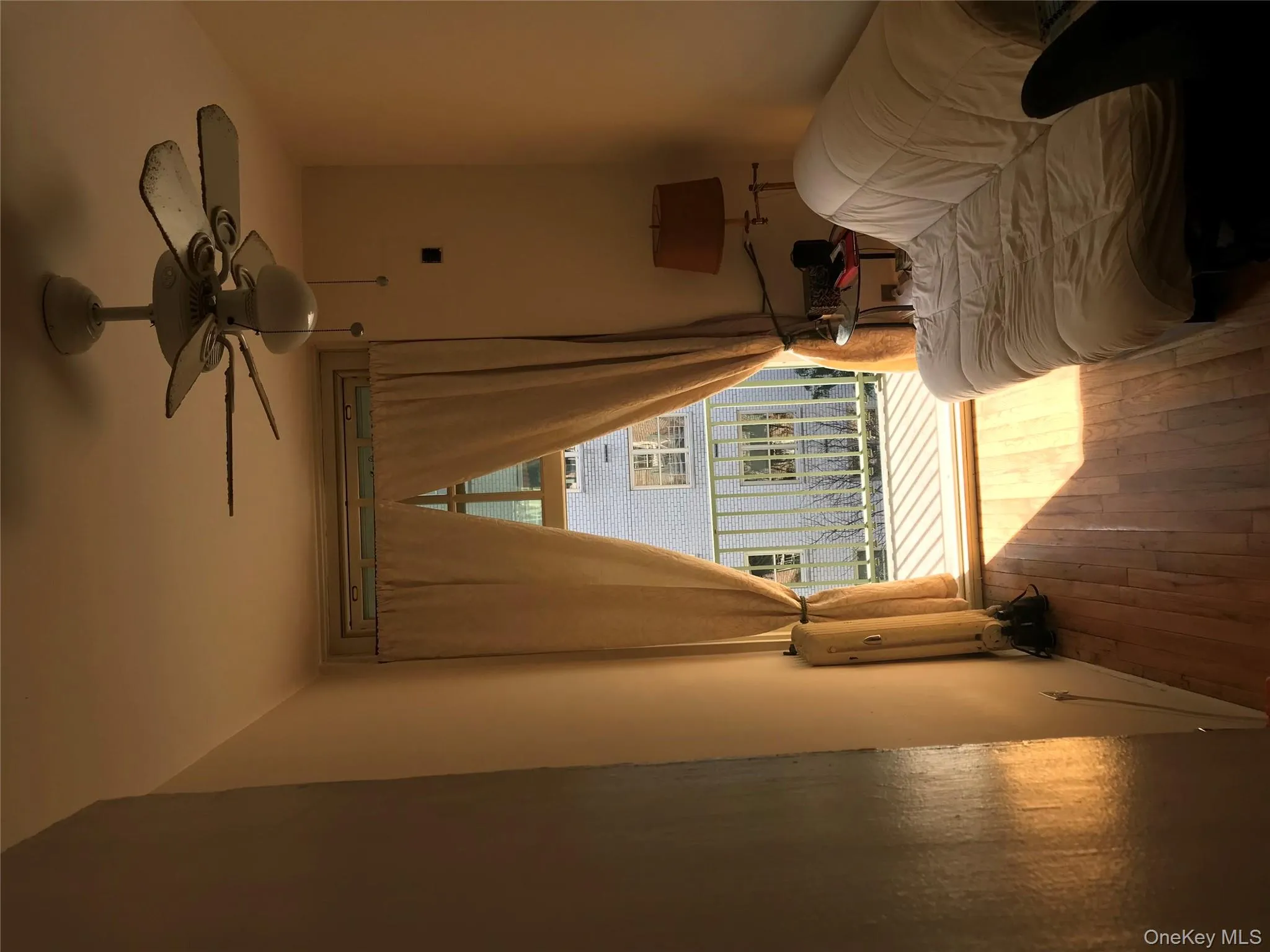 Living area with a ceiling fan, hardwood / wood-style floors, and radiator heating unit Living area with a ceiling fan, hardwood / wood-style floors, and radiator heating unit