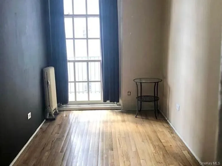 Unfurnished room with light wood-style flooring and radiator heating unit Unfurnished room with light wood-style flooring and radiator heating unit