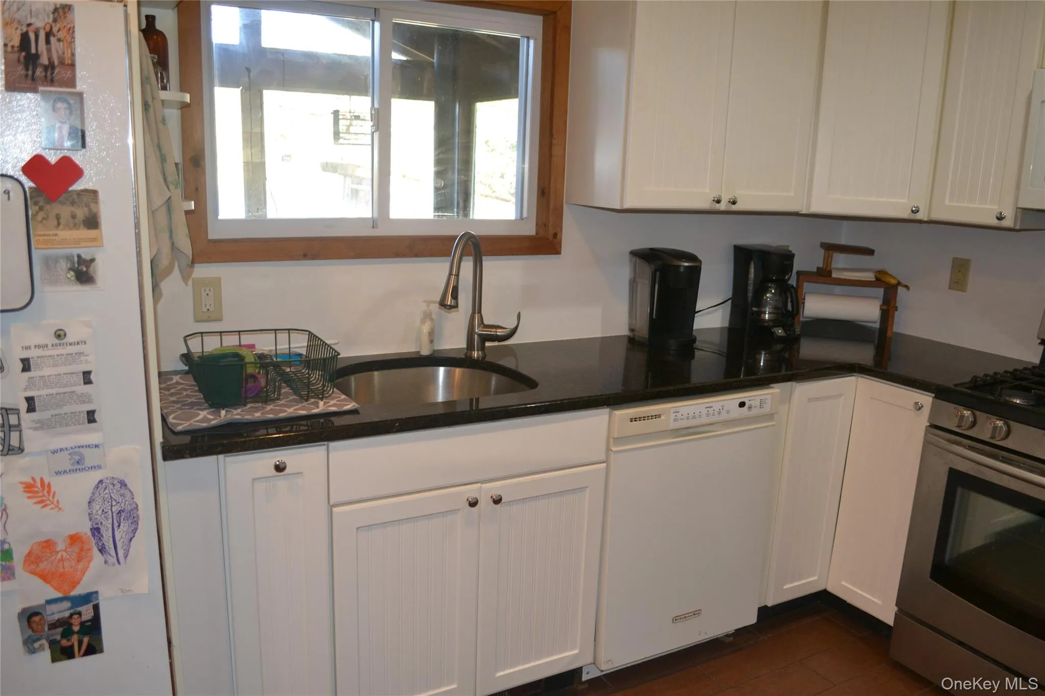 Kitchen featuring white appliances, dark stone counters, and white cabinets Kitchen featuring white appliances, dark stone counters, and white cabinets