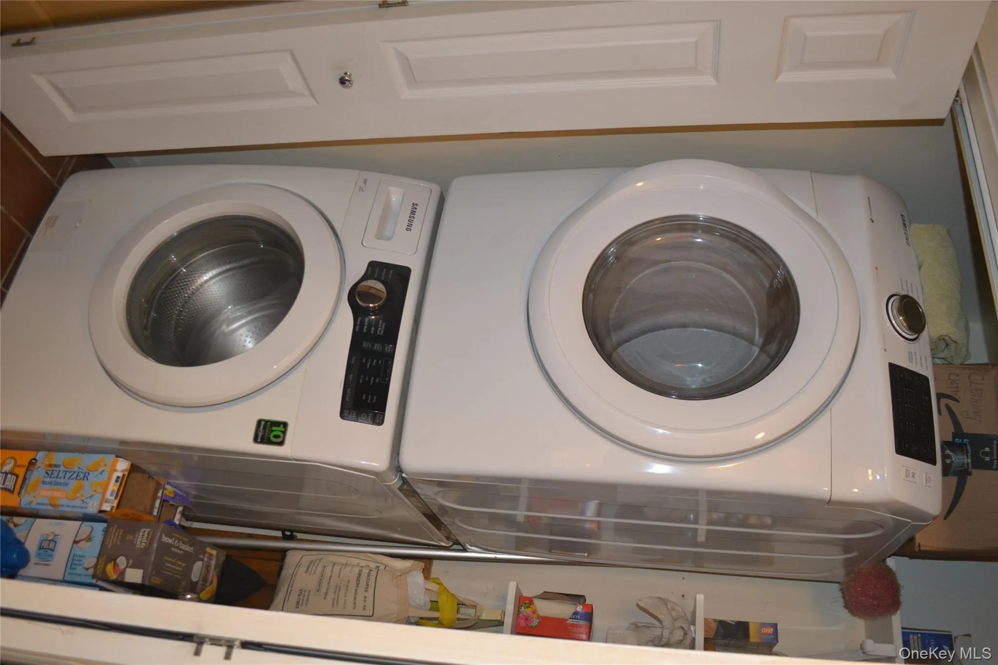 Laundry room featuring stacked washer / dryer and dark tile patterned flooring Laundry room featuring stacked washer / dryer and dark tile patterned flooring