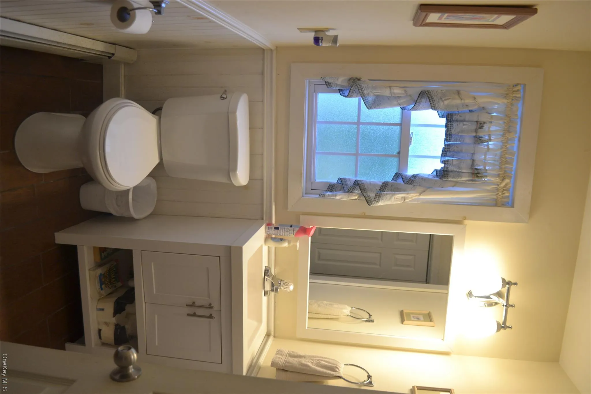 Bathroom featuring baseboard heating, vanity, and a wainscoted wall Bathroom featuring baseboard heating, vanity, and a wainscoted wall