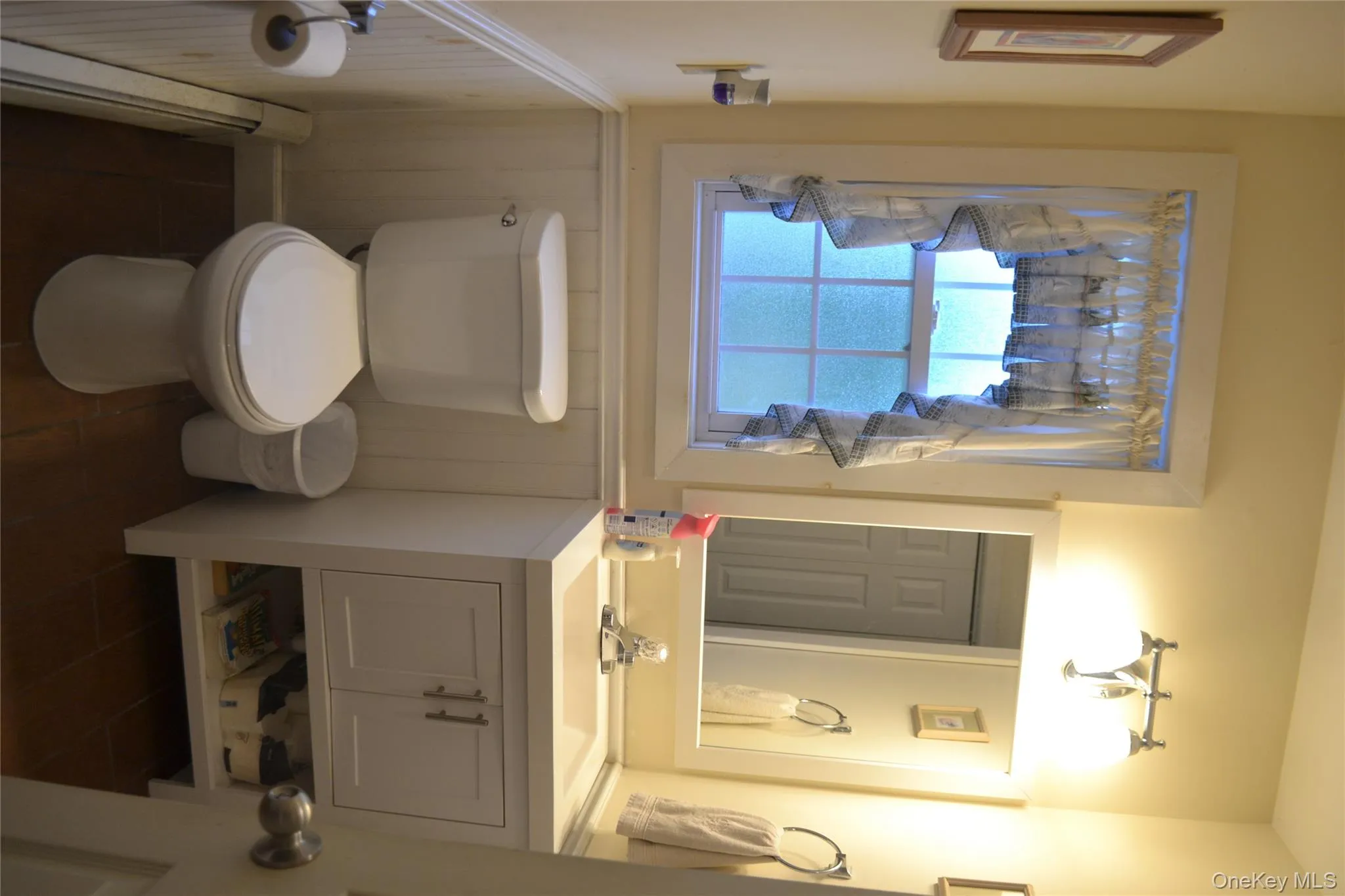 Bathroom featuring baseboard heating, vanity, and a wainscoted wall Bathroom featuring baseboard heating, vanity, and a wainscoted wall