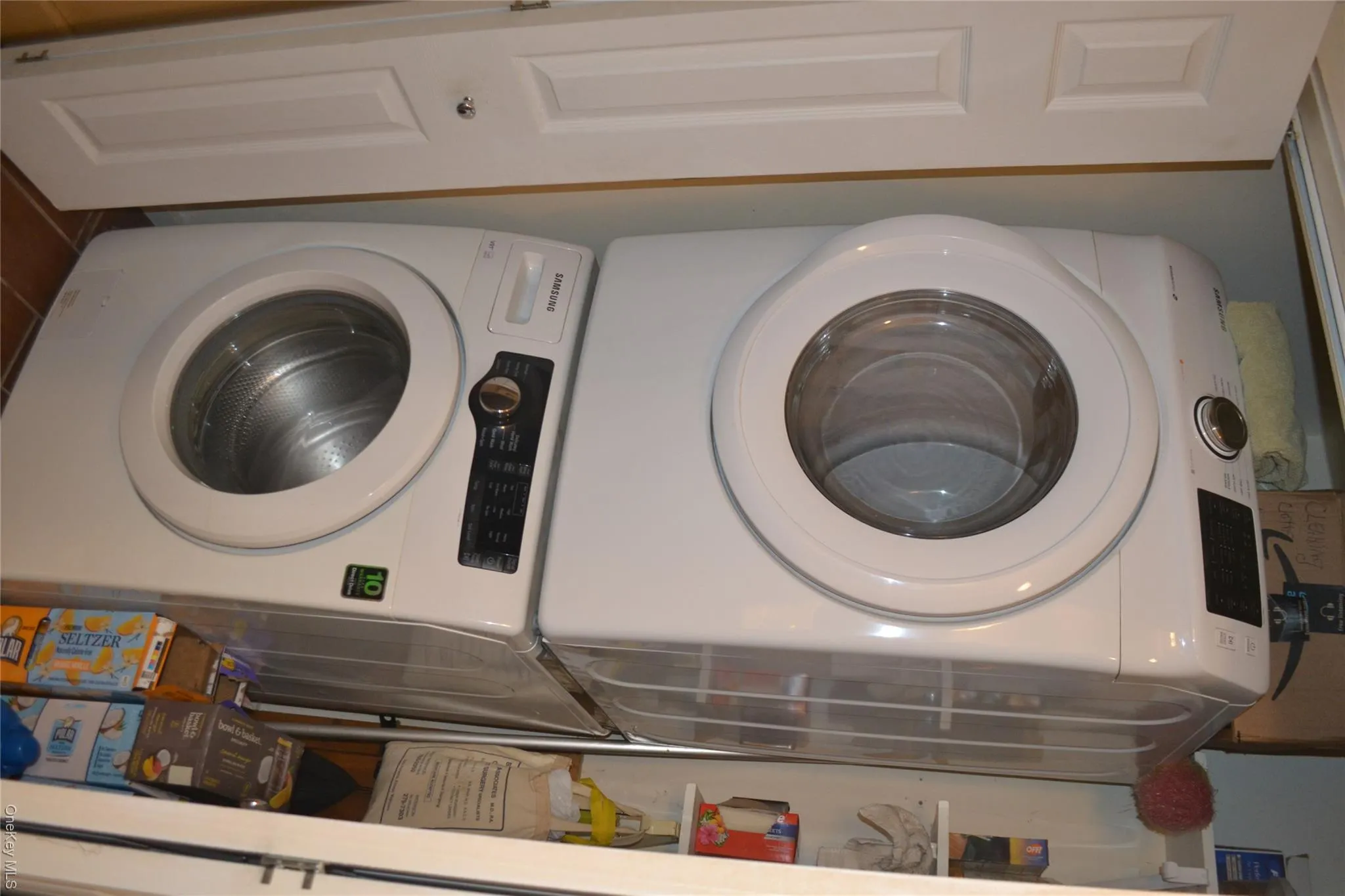 Laundry room featuring stacked washer / dryer and dark tile patterned flooring Laundry room featuring stacked washer / dryer and dark tile patterned flooring
