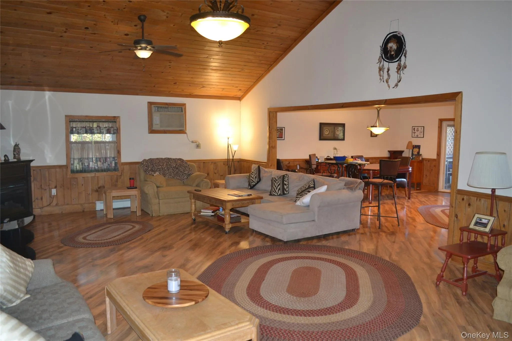 Living room with wood ceiling, wood finished floors, lofted ceiling, a wainscoted wall, and wooden walls Living room with wood ceiling, wood finished floors, lofted ceiling, a wainscoted wall, and wooden walls