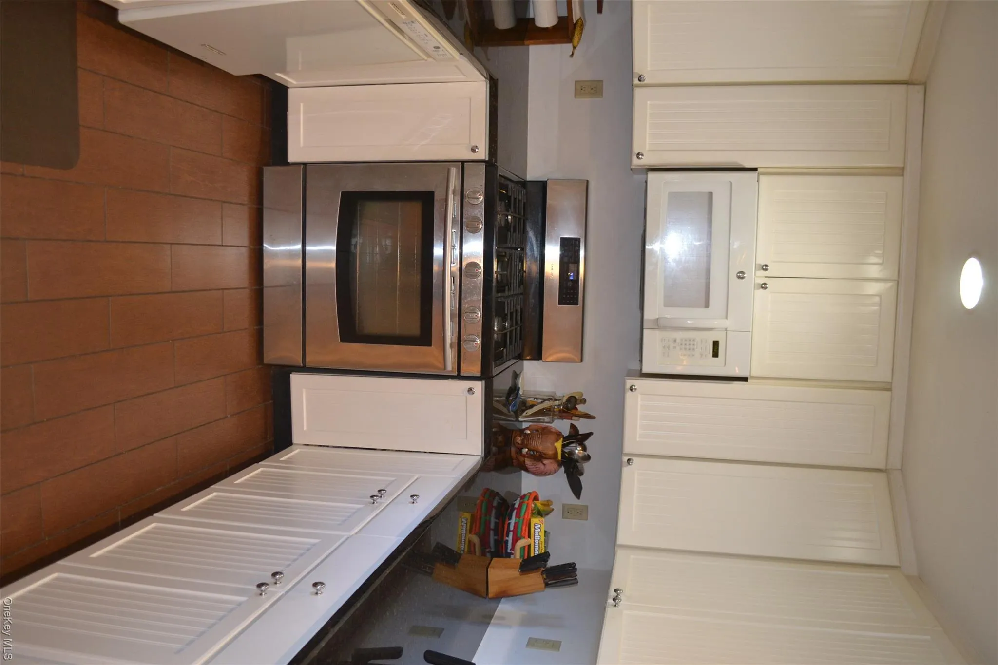 Kitchen with appliances with stainless steel finishes, dark stone countertops, white cabinets, recessed lighting, and dark wood-type flooring Kitchen with appliances with stainless steel finishes, dark stone countertops, white cabinets, recessed lighting, and dark wood-type flooring