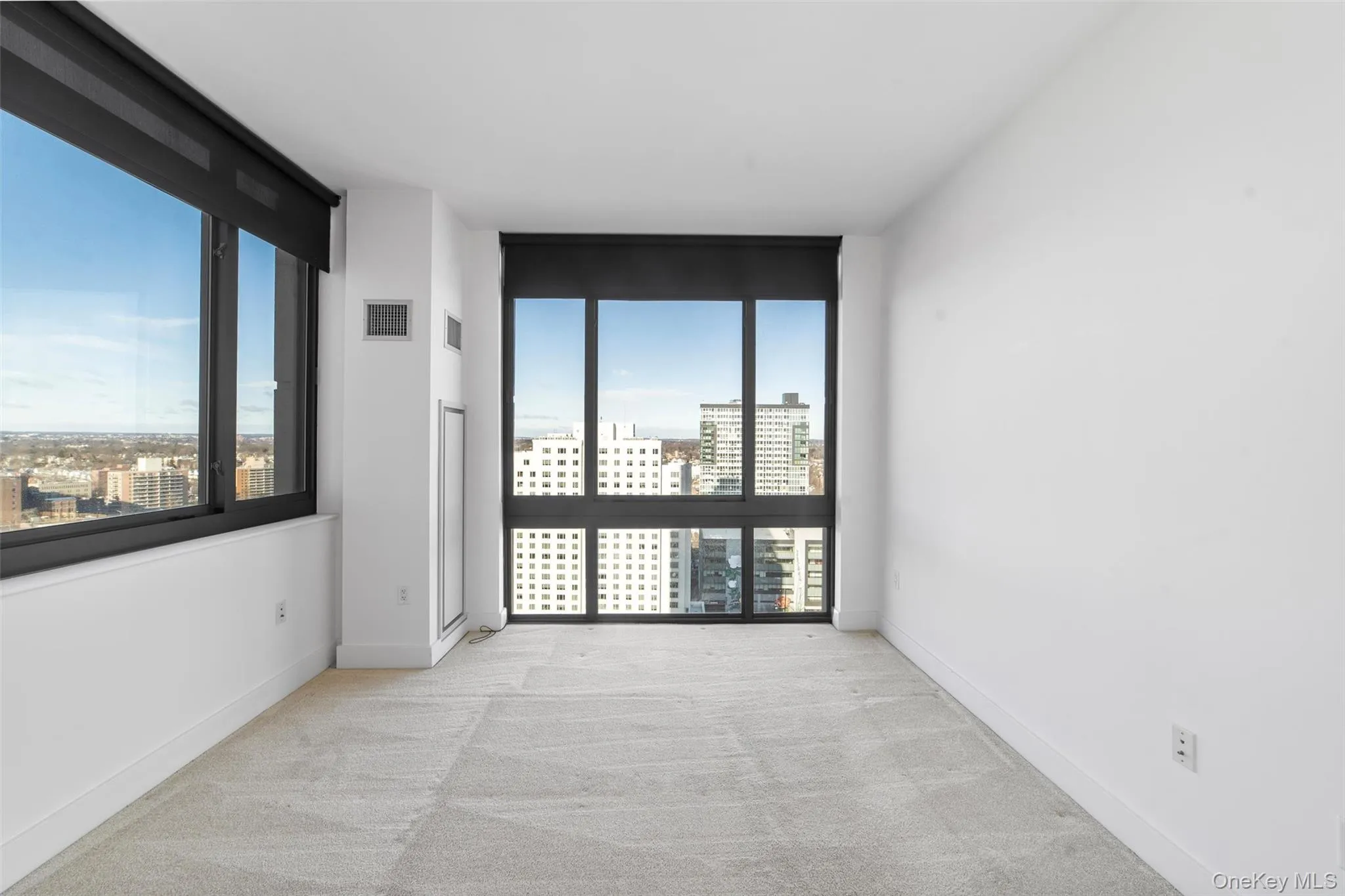 Unfurnished room featuring plenty of natural light, light colored carpet, a view of city, and expansive windows Unfurnished room featuring plenty of natural light, light colored carpet, a view of city, and expansive windows