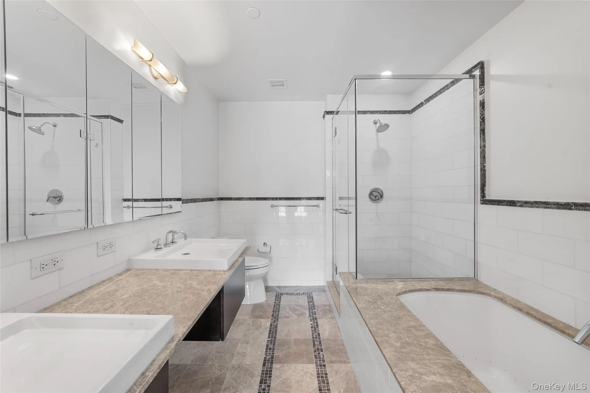 Full bath featuring tile walls, a garden tub, double vanity, a shower stall, and light tile patterned floors Full bath featuring tile walls, a garden tub, double vanity, a shower stall, and light tile patterned floors