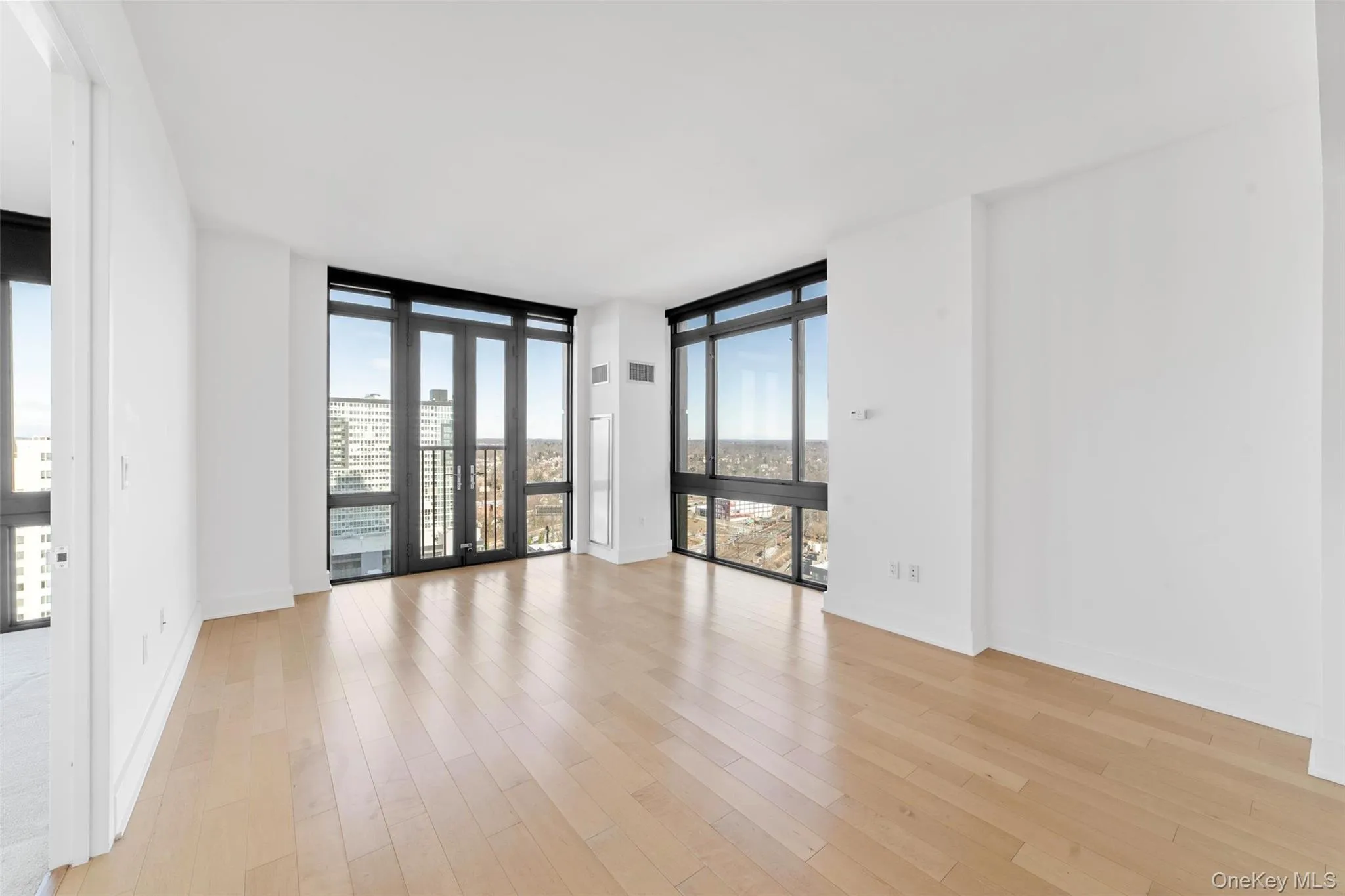 Unfurnished room with a wall of windows, light wood-style floors, and a city view Unfurnished room with a wall of windows, light wood-style floors, and a city view