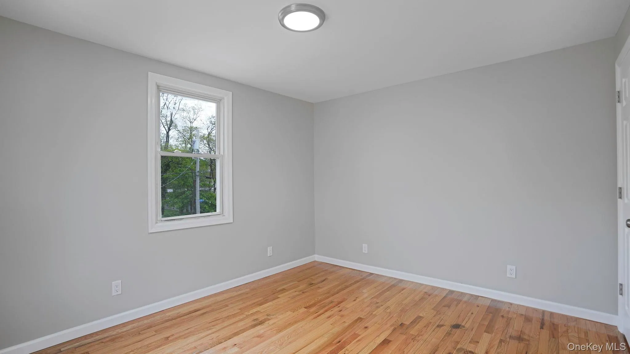 Spare room featuring light wood-style floors and baseboards Spare room featuring light wood-style floors and baseboards