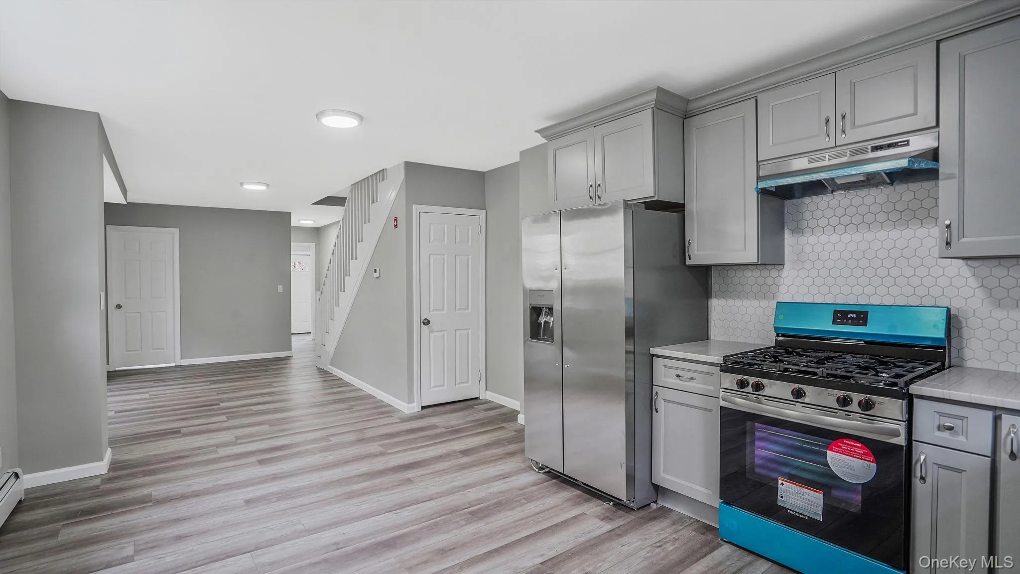 Kitchen with appliances with stainless steel finishes, gray cabinetry, and under cabinet range hood Kitchen with appliances with stainless steel finishes, gray cabinetry, and under cabinet range hood
