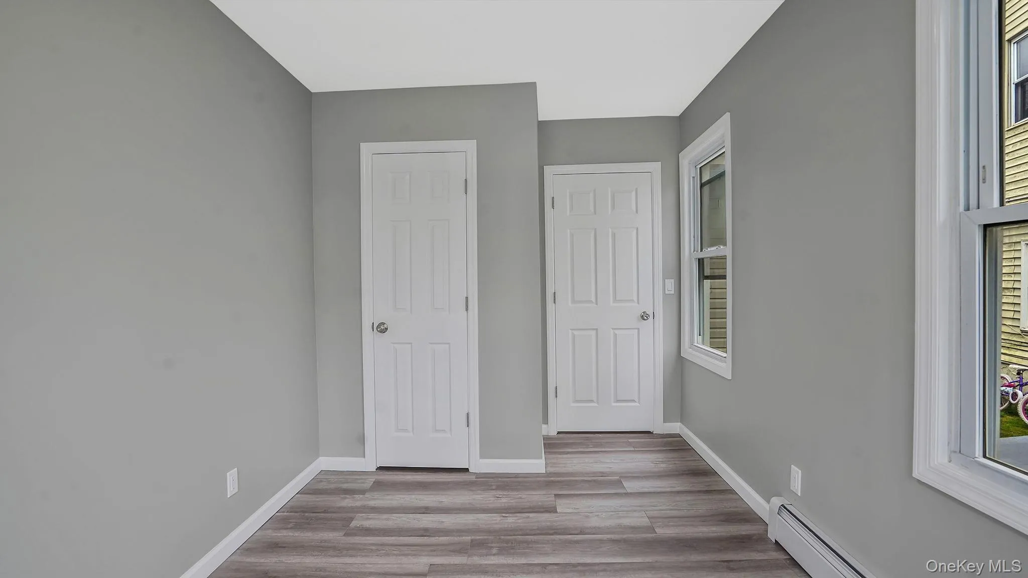 Unfurnished bedroom with baseboard heating and light wood-style flooring Unfurnished bedroom with baseboard heating and light wood-style flooring