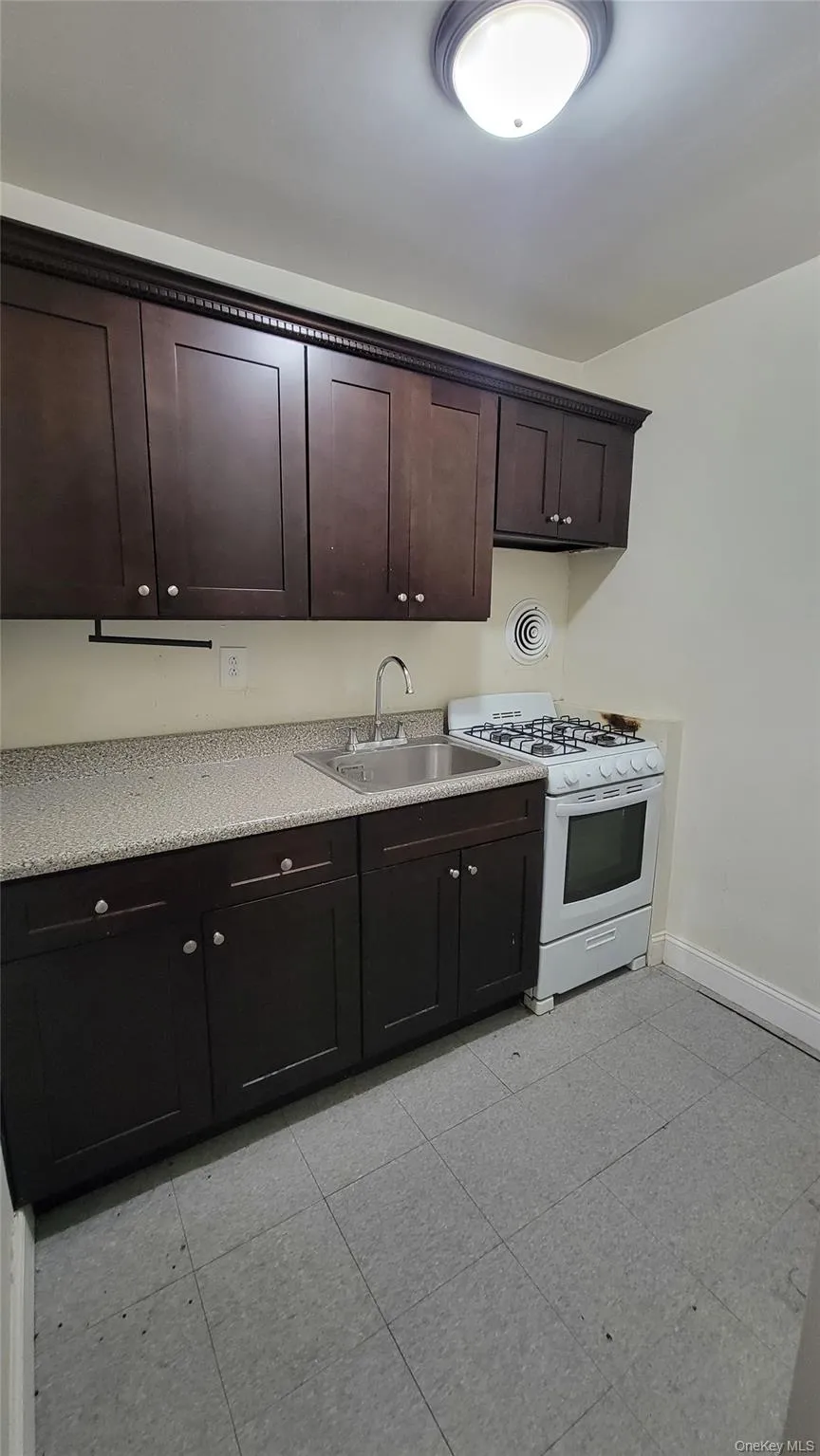 Kitchen featuring dark brown cabinetry and white gas stove Kitchen featuring dark brown cabinetry and white gas stove