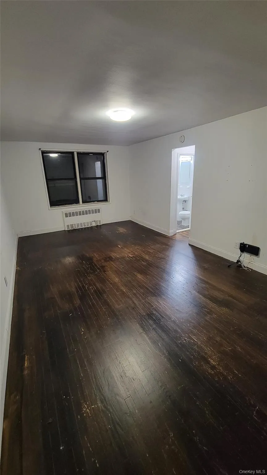 Unfurnished room with dark wood-type flooring and radiator heating unit Unfurnished room with dark wood-type flooring and radiator heating unit