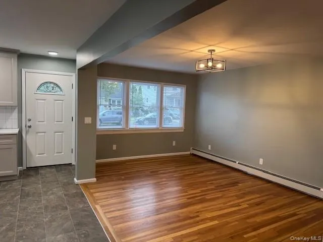 Entryway featuring baseboard heating, a chandelier, and dark wood-style flooring Entryway featuring baseboard heating, a chandelier, and dark wood-style flooring
