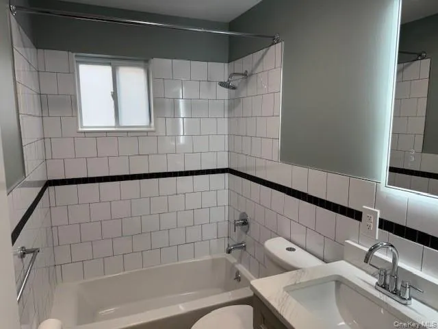 Bathroom with shower / bath combination, vanity, and tile walls Bathroom with shower / bath combination, vanity, and tile walls