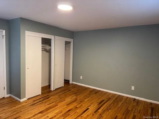 Unfurnished bedroom with multiple closets and wood finished floors Unfurnished bedroom with multiple closets and wood finished floors