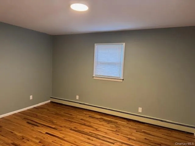 Spare room with baseboard heating and wood finished floors Spare room with baseboard heating and wood finished floors