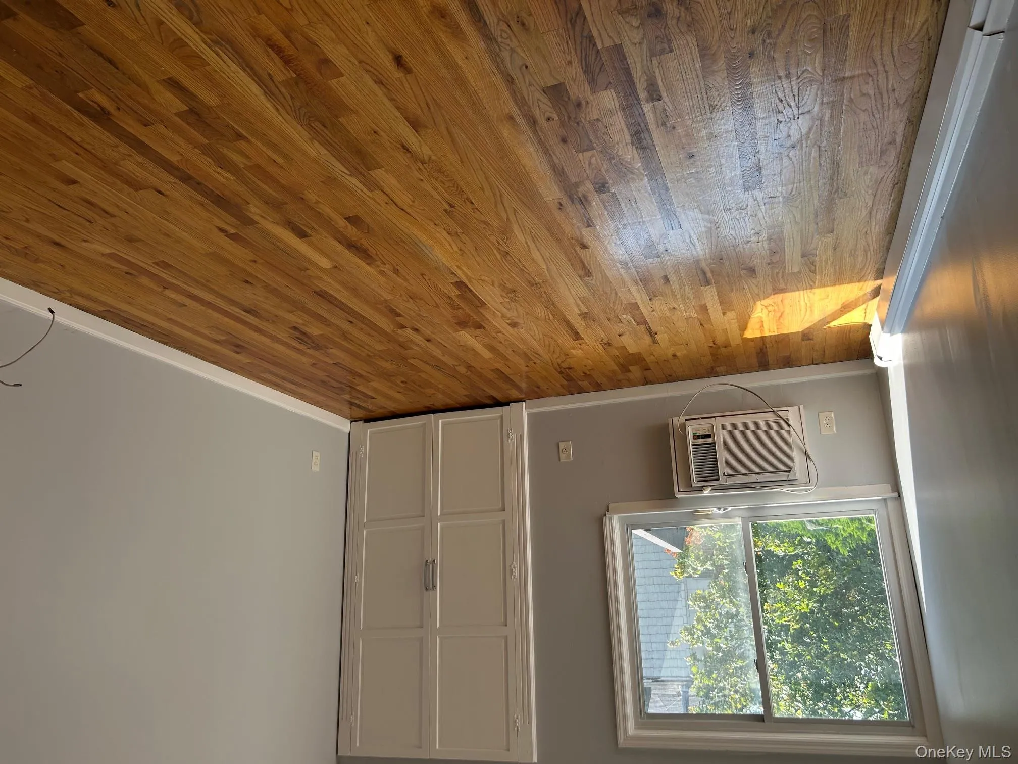 Unfurnished bedroom with wood-type flooring and a wall mounted AC Unfurnished bedroom with wood-type flooring and a wall mounted AC