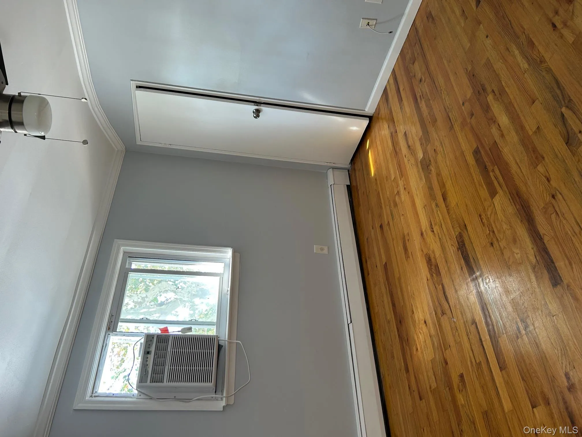 Unfurnished room with a baseboard heating unit, crown molding, light wood-type flooring, and cooling unit Unfurnished room with a baseboard heating unit, crown molding, light wood-type flooring, and cooling unit