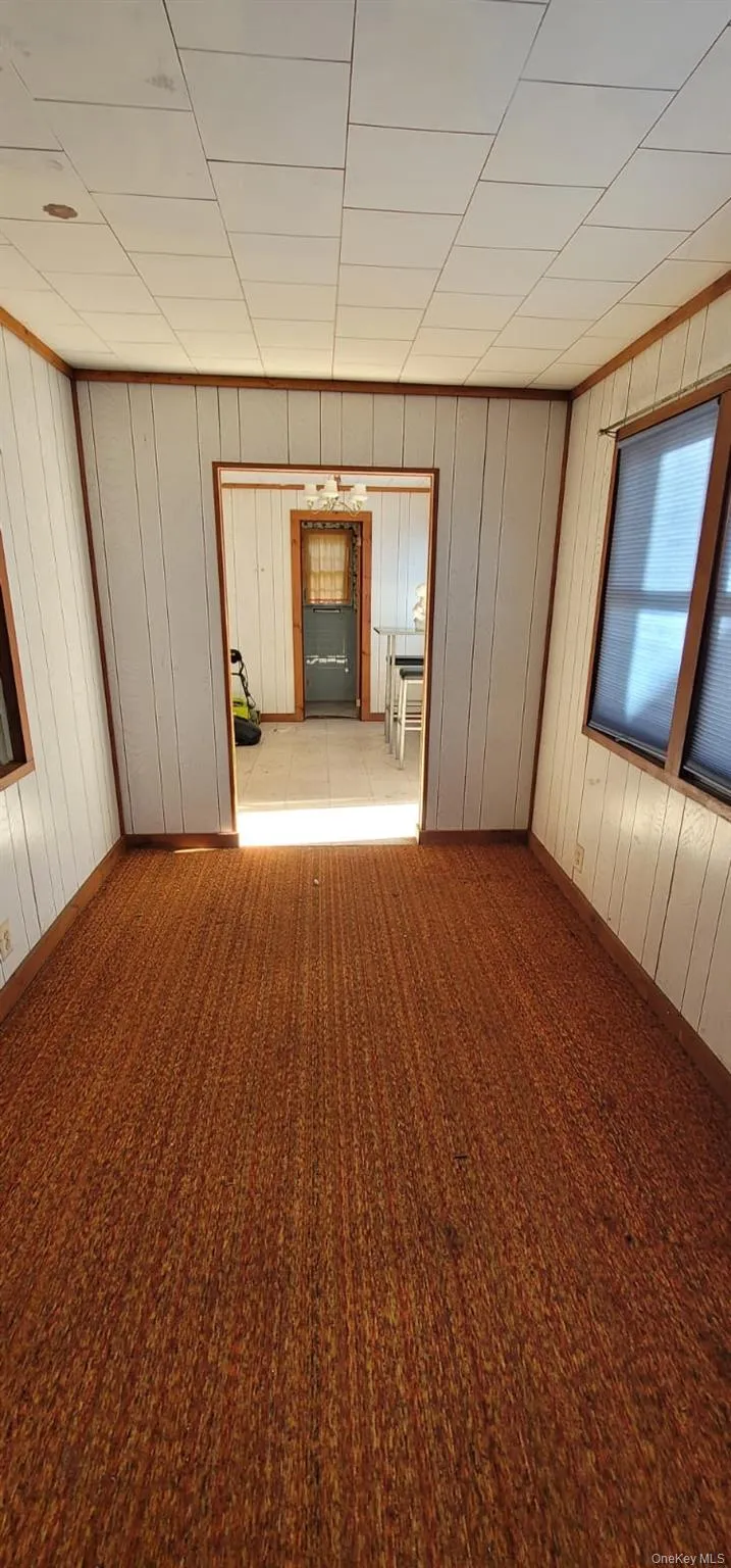 Empty room featuring baseboards and wooden walls Empty room featuring baseboards and wooden walls