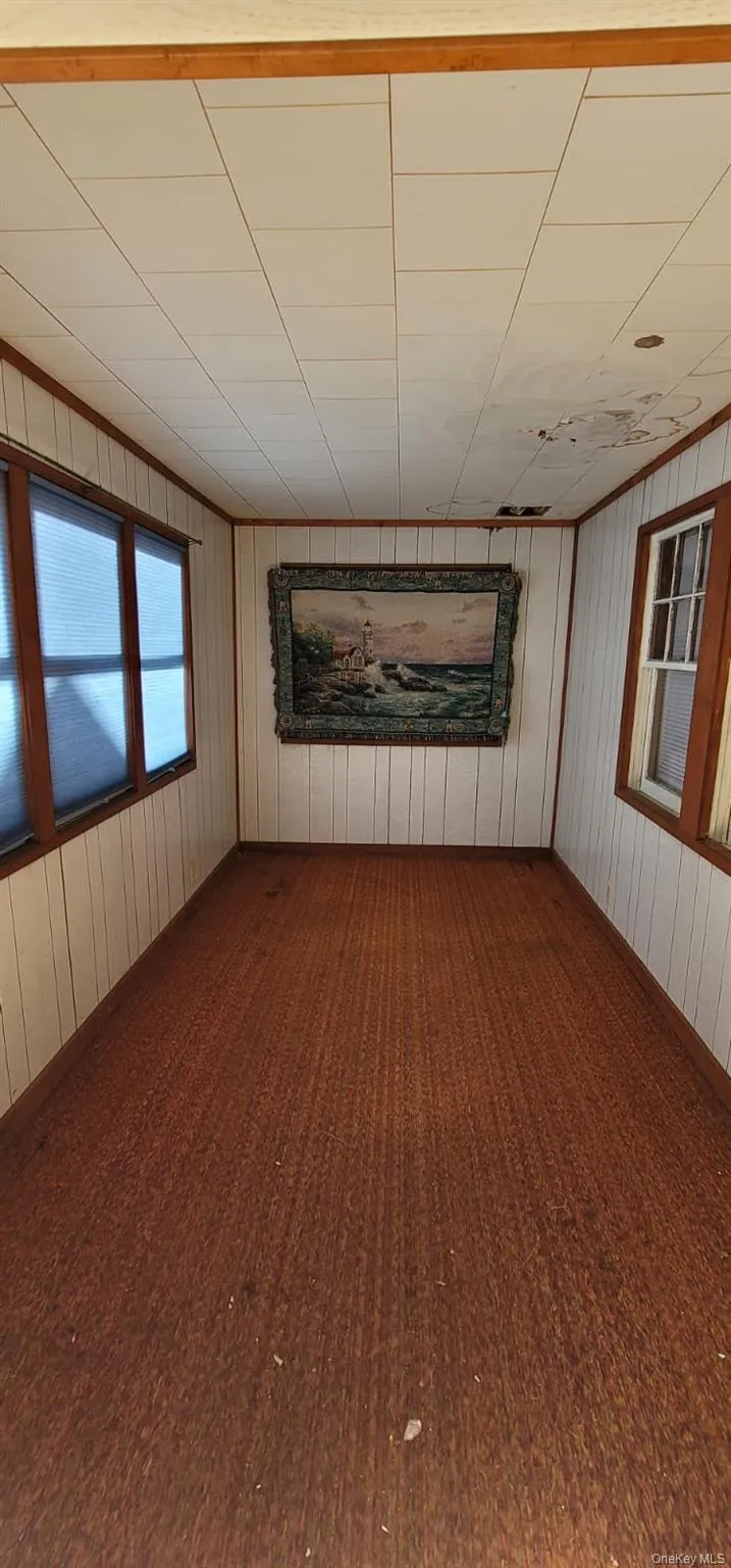 Unfurnished room featuring wooden walls and baseboards Unfurnished room featuring wooden walls and baseboards