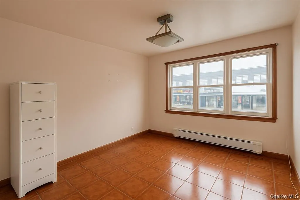 Unfurnished room with baseboard heating and light tile patterned flooring Unfurnished room with baseboard heating and light tile patterned flooring