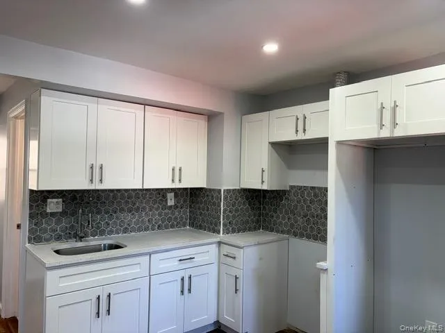 1st fl Kitchen with white cabinetry, decorative backsplash, light stone counters, and recessed lighting 1st fl Kitchen with white cabinetry, decorative backsplash, light stone counters, and recessed lighting