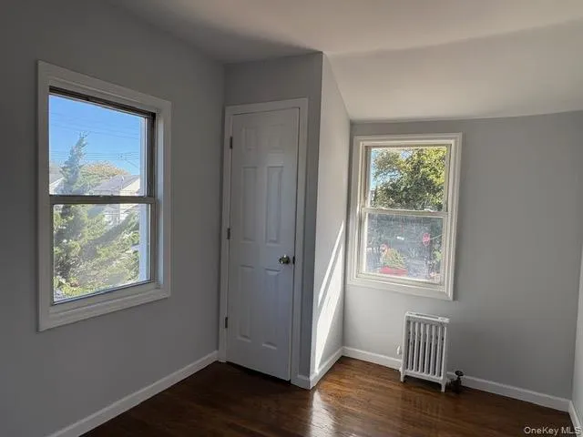 \bedroom with radiator heating unit and dark wood-style flooring \bedroom with radiator heating unit and dark wood-style flooring