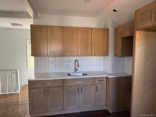 Kitchen featuring brown cabinets, tasteful backsplash, light stone countertops, and recessed lighting Kitchen featuring brown cabinets, tasteful backsplash, light stone countertops, and recessed lighting
