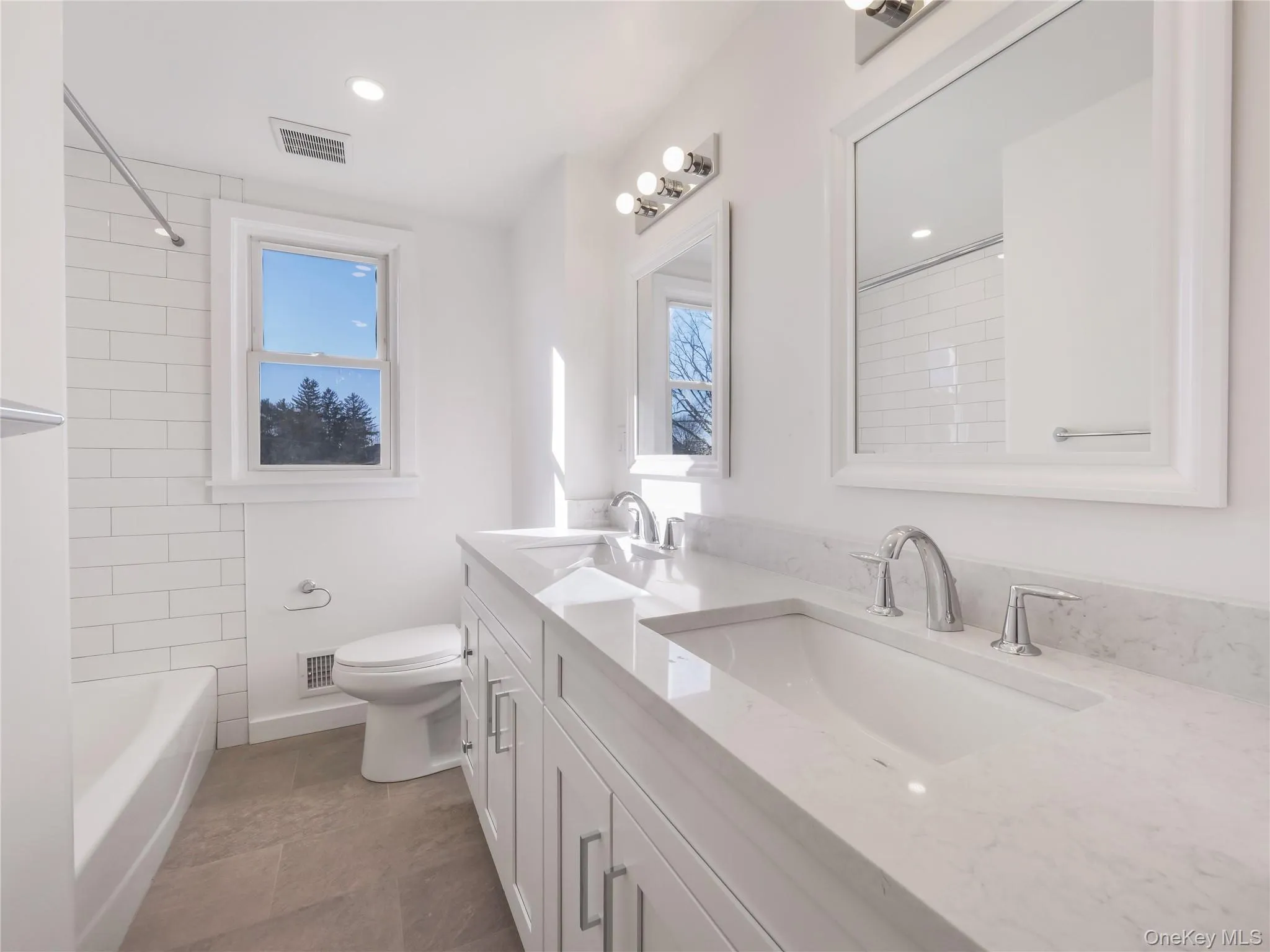 Full bathroom featuring tiled shower / bath, a healthy amount of sunlight, toilet, and vanity Full bathroom featuring tiled shower / bath, a healthy amount of sunlight, toilet, and vanity