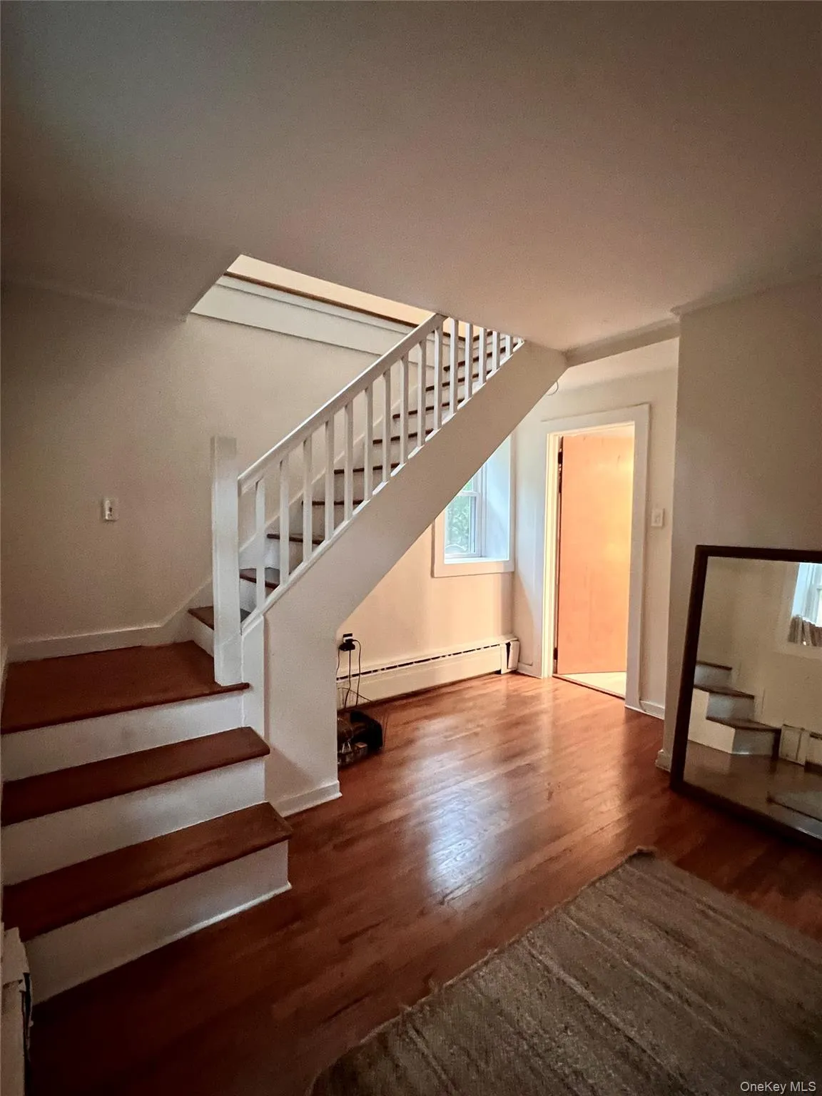 Bonus room featuring stairs, dark wood-type flooring, a baseboard heating unit, and baseboard heating Bonus room featuring stairs, dark wood-type flooring, a baseboard heating unit, and baseboard heating