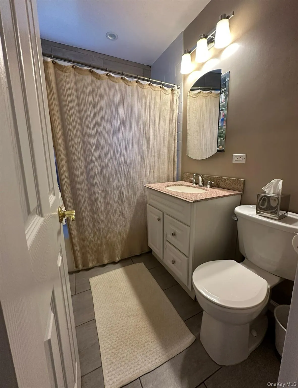 Full bath featuring vanity, a shower with shower curtain, and light tile patterned flooring Full bath featuring vanity, a shower with shower curtain, and light tile patterned flooring