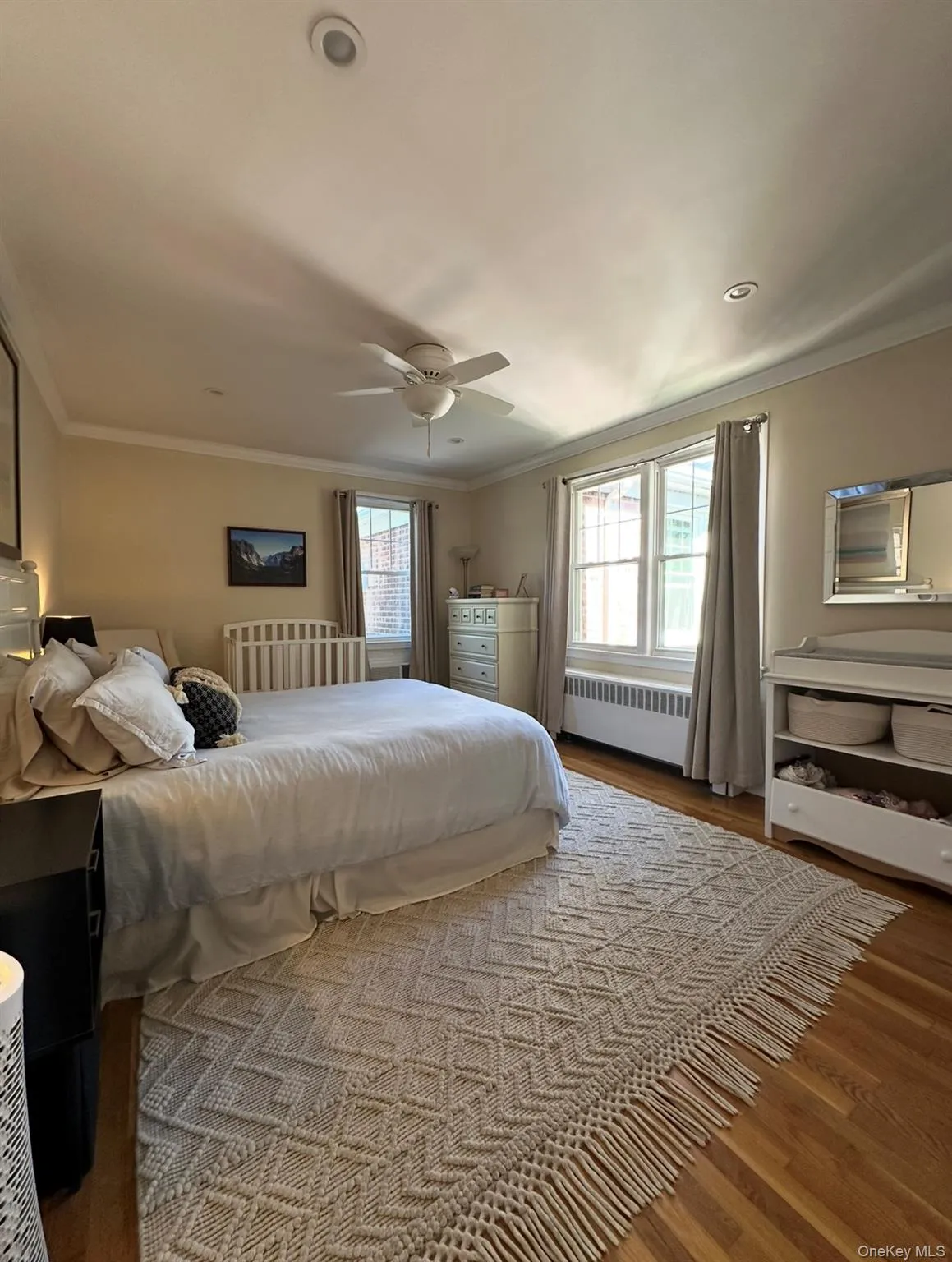 Bedroom with crown molding, wood finished floors, radiator, and a ceiling fan Bedroom with crown molding, wood finished floors, radiator, and a ceiling fan