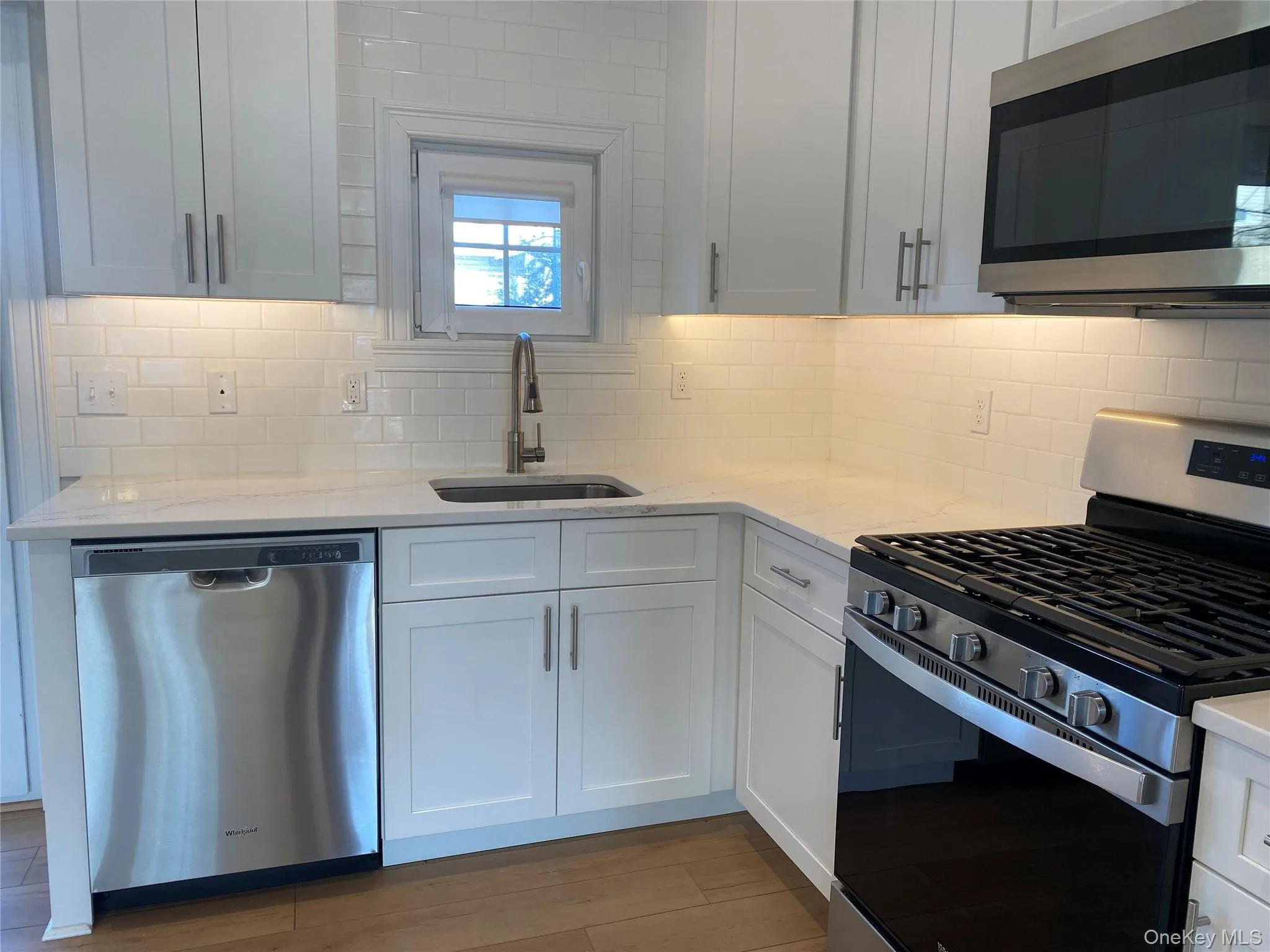 Kitchen featuring stainless steel appliances, light stone countertops, and white cabinets Kitchen featuring stainless steel appliances, light stone countertops, and white cabinets