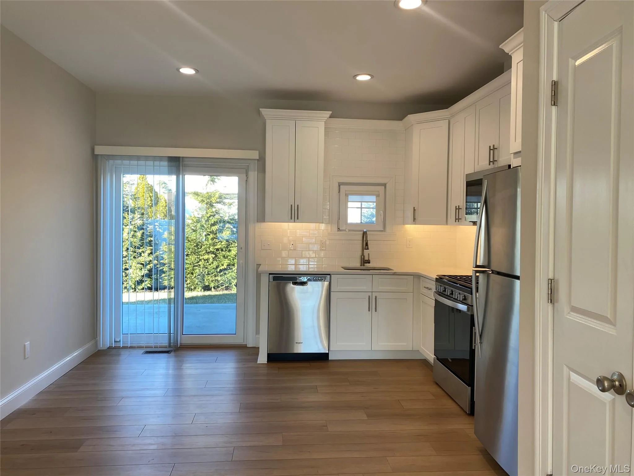 Kitchen featuring white cabinetry, decorative backsplash, appliances with stainless steel finishes, dark wood finished floors, and recessed lighting Kitchen featuring white cabinetry, decorative backsplash, appliances with stainless steel finishes, dark wood finished floors, and recessed lighting