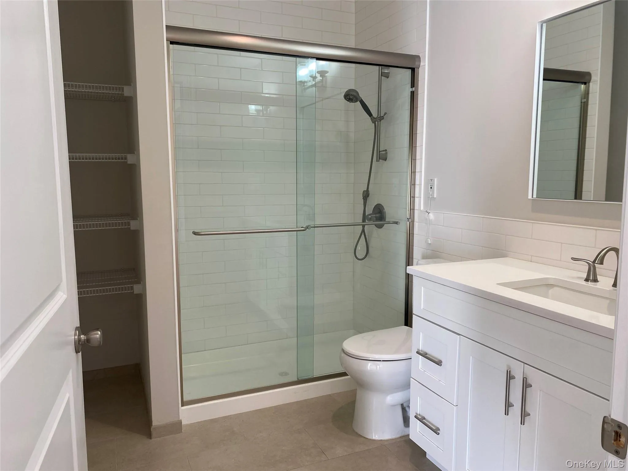 Bathroom featuring vanity, a shower stall, light tile patterned floors, and tile walls Bathroom featuring vanity, a shower stall, light tile patterned floors, and tile walls