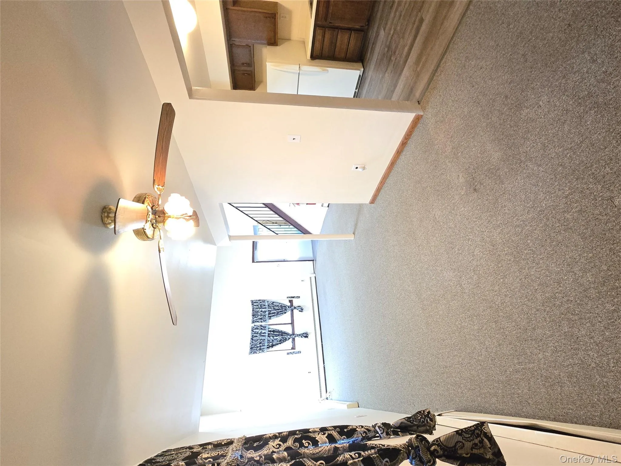 Unfurnished living room with light colored carpet, ceiling fan, and a baseboard heating unit Unfurnished living room with light colored carpet, ceiling fan, and a baseboard heating unit